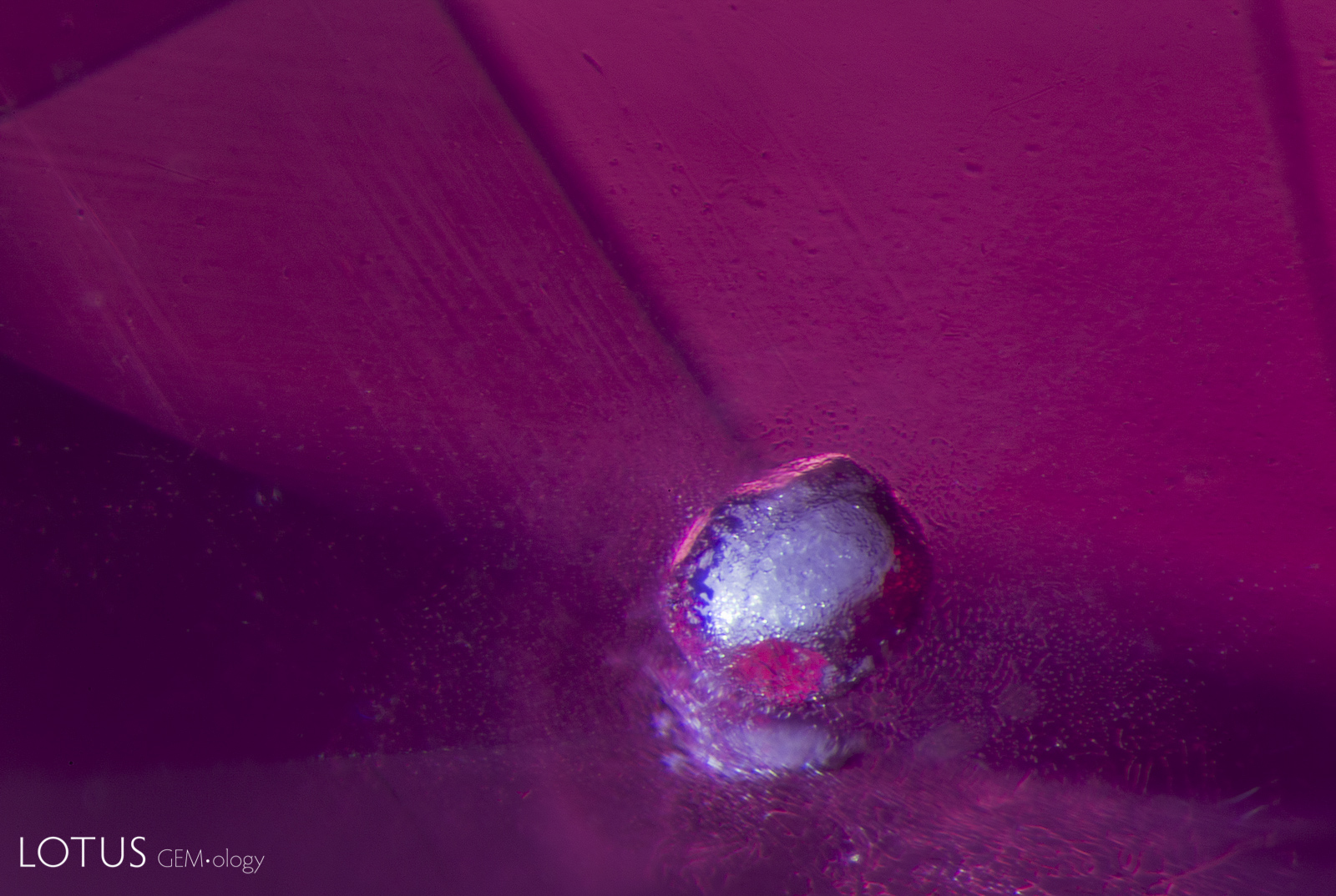 This melted crystal shows a &ldquo;frosty&rdquo; appearance similar to that of a snowball. The vast majority of spinels that we see in our lab are untreated, but this is a rare example of a heated spinel. The host of this melted crystal is a Mahenge, Tanzania, spinel. Darkfield + Diffuse oblique fiber optic illumination. Photo: E. Billie Hughes