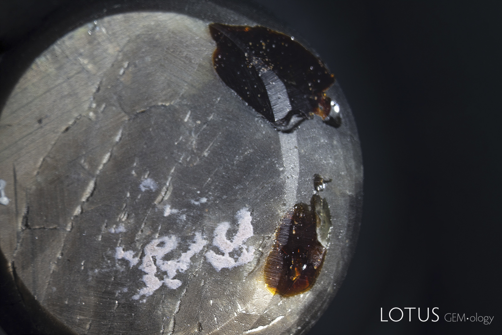 Left: Two large pits on the back of the star sapphire in question. One can see the brown dopping varnish (the white areas are adhesive from tape).