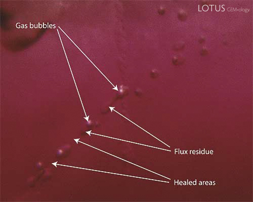 Figure 10. Flux residue may be two-phase Highly magnified photo showing flux residue within a flux-healed Mong Hsu ruby. Note that the small flux-filled pockets may contain gas bubbles formed by contraction of the flux residue as it cools. Photo: R.W. Hughes