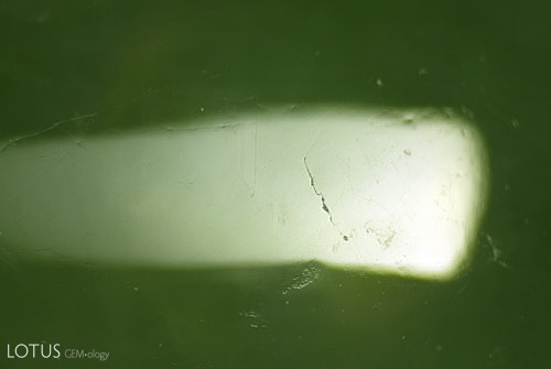 In contrast, the surface of an untreated jadeite shows only major cracks. Absent is the network of tiny microfractures created by bleaching