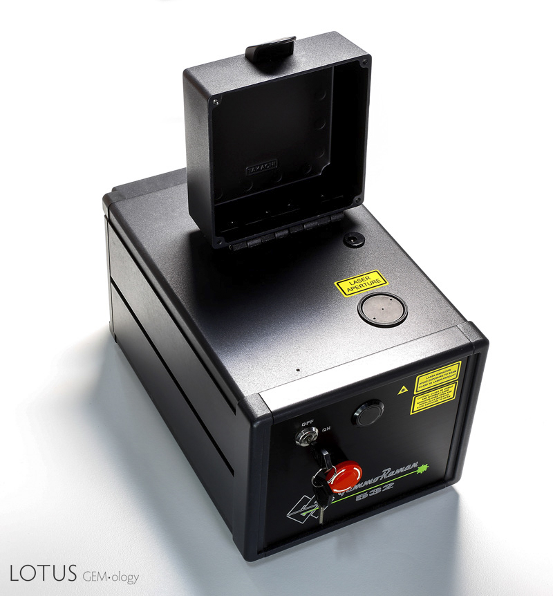 Figure 2: The GemmoRaman-532 (2014 version) with the lid open. Next to the yellow "laser aperature" sticker is the round sample stage. Specimens to be tested are placed over the center hole. Photo: E. Billie Hughes/Lotus Gemology
