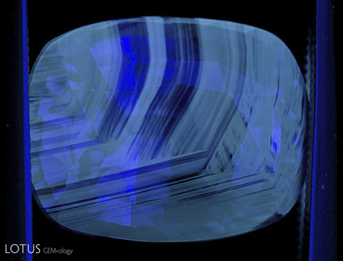 Figure 4. Another blue sapphire showing chalky fluorescence corresponding to the colorless portions of the gem. When seen, this strong chalky blue to green SW fluorescence is an extremely strong indication that the gem has been subjected to high-temperature heat treatment. Note that this fluorescence often appears in patterns that resemble the graining of wood. Photo: Richard W. Hughes; Nikon D200