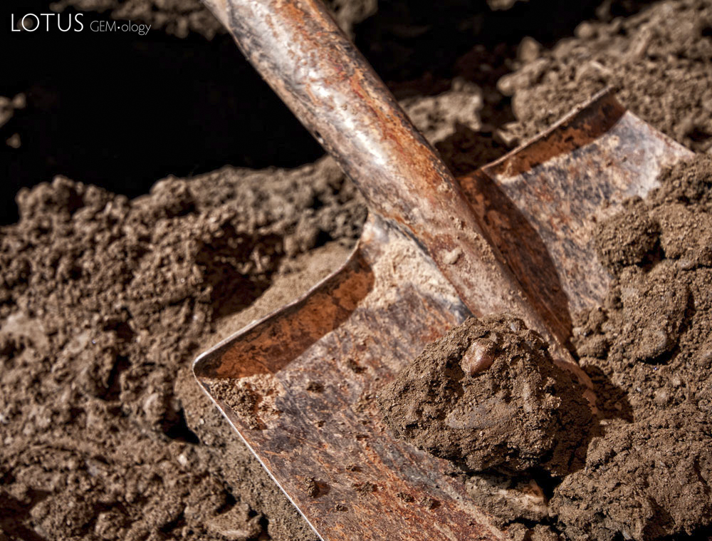 Figure 10. A mud-covered piece of andesine lies in a shovel in Lower Yu Lin Gu valley, near Zha Lin village. Photo: Richard W. Hughes