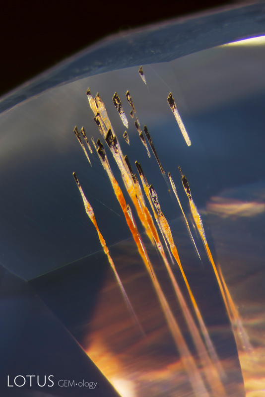 Surface-reaching growth tubes within a sapphire exhibit unaltered yellowish staining, an&nbsp;indication that the stone has probably not been heated. Combined with other observations,&nbsp;this suggests a possible Madagascar origin. Photomicrograph by E. Billie Hughes;&nbsp;horizontal field of view 1.4 mm.