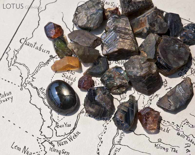 Rough gems from Khao Ploi Waen, along with one 12-rayed black star sapphire cabochon. The deep red stones are zircon; the rest are sapphire. Photo &copy; Wimon Manorotkul.