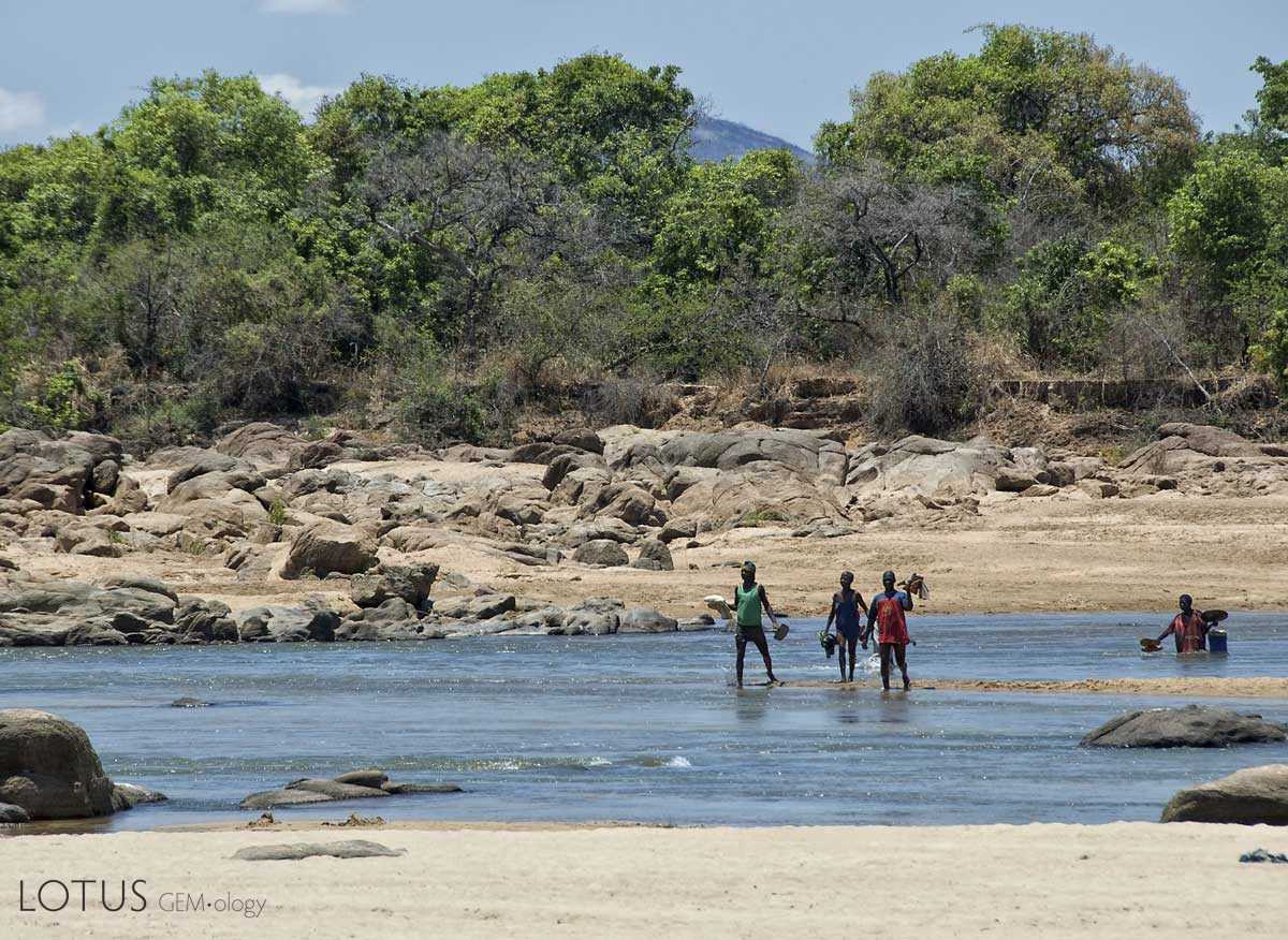 Miners fording the Ruvuma river that separates Tanzania (near bank) from Mozambique (far bank), in Tanzania's Tunduru district. Gems are found on both sides of the river. Photo: Richard W. Hughes