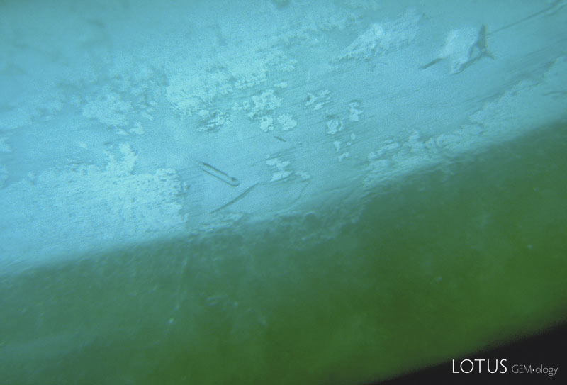 Figure 31. In some B-jade, such as this bangle bracelet, resin-filled areas can be seen under the microscope in reflected light. Photo &copy; Richard W. Hughes