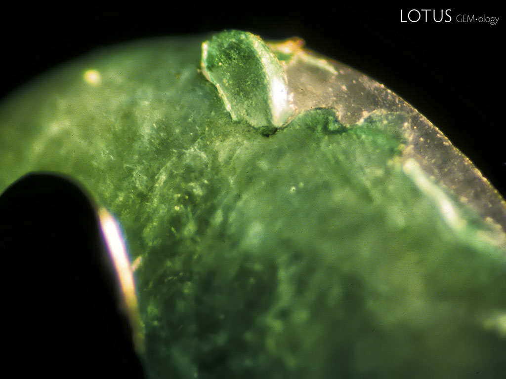 Bottom: A plastic-coated jadeite cabochon displays peeling of the green plastic at the girdle under magnification. Photos &copy; Richard W. Hughes