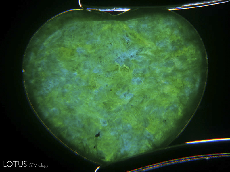 This heart-shaped jadeite cabochon is actually hollowed out to near-eggshell thickness so that the color appears bright and lively. To protect it, the back is filled in with resin. Such stones are normally bezel set with a closed backing to hide the fraud.