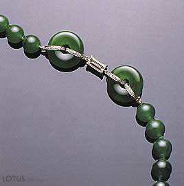 Figure 23. This necklace, which contains a total of 65 beads (7.8&ndash;9.8 mm in diameter) and two matching hoops, illustrates the optimum "vivid emerald green" color in fine jadeite. Note also the very fine "old mine" texture and translucency. Photo courtesy of and &copy; Christie's Hong Kong and Tino Hammid.