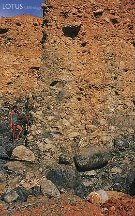 Figure 4. At the Ka Htan West mine, located between Lonkin and Tawmaw, large peridotite boulders can be seen at the base of this 15-m-high wall of Uru Boulder Conglomerate. Photo &copy; George Bosshart.