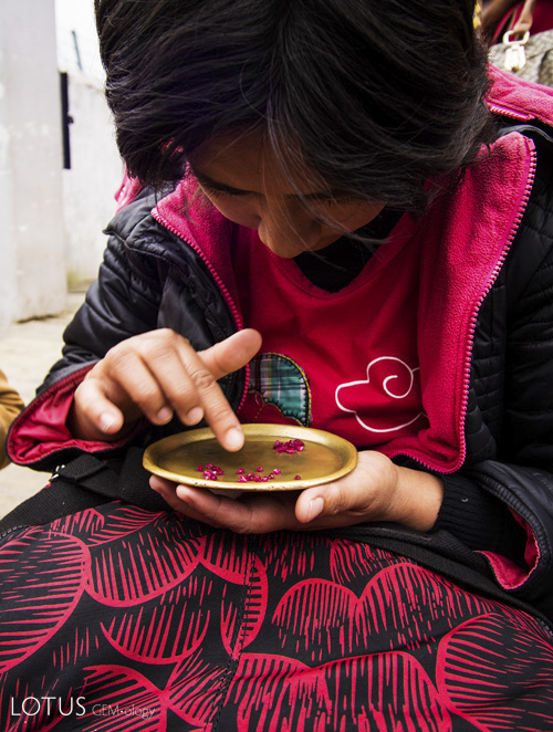 Figure 6. A woman sorts stones in Mogok&rsquo;s market. Brass trays were originally used to enhance the color of red stones, but have become so ubiquitous that now buyers bring their own brass trays.&nbsp;Photo: E. Billie Hughes