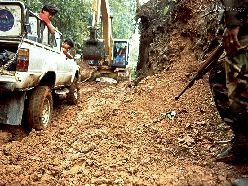 Utilizing its mechanical arm, a backhoe drags our truck out of Hweka